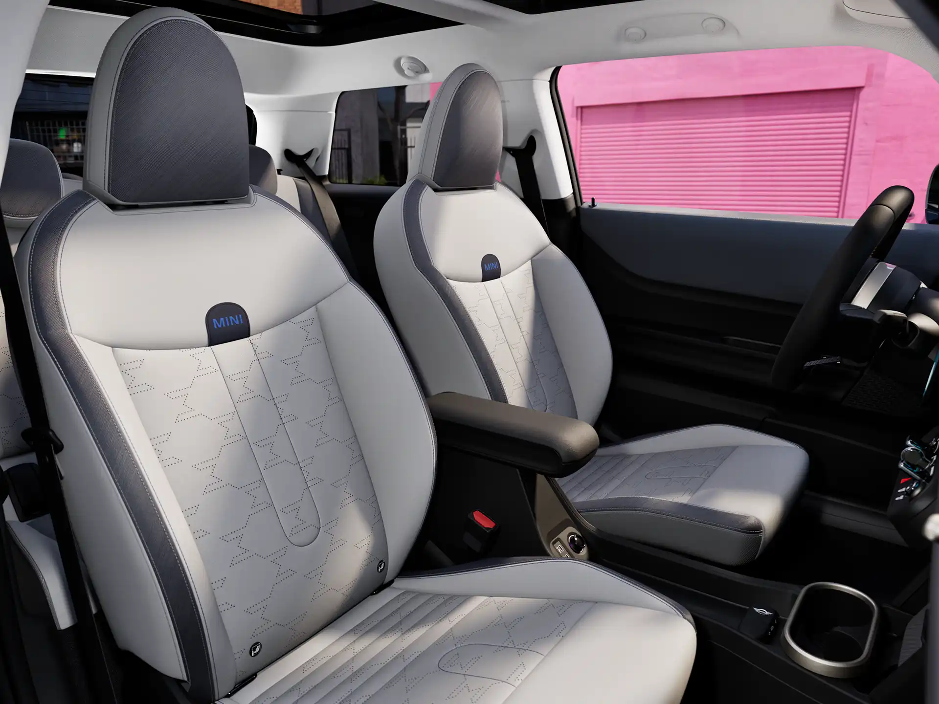 Binnenaanzicht van de MINI Cooper toont het dashboard, het stuurwiel, het ronde display, het glazen panoramadak en de achterkant van de voorstoelen.